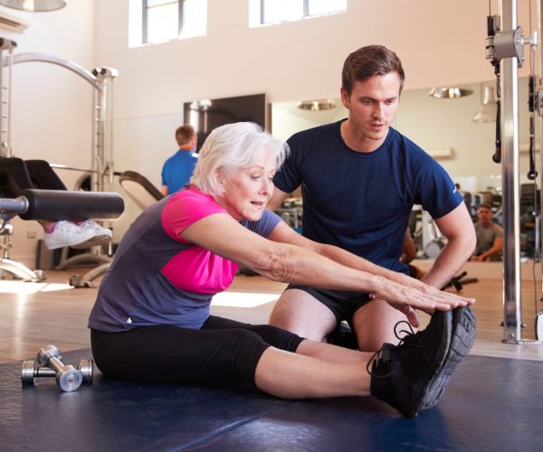 senior-woman-exercising-in-gym-being-encouraged-ADB54EP.jpg